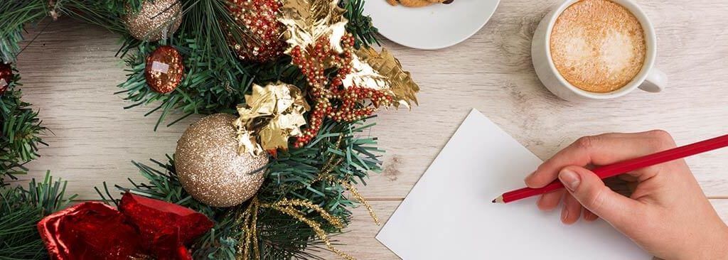 Christmas Marketing Ideas for Small Businesses 2017 - person making notes with pen and paper on a tabletop with Christmas wreath