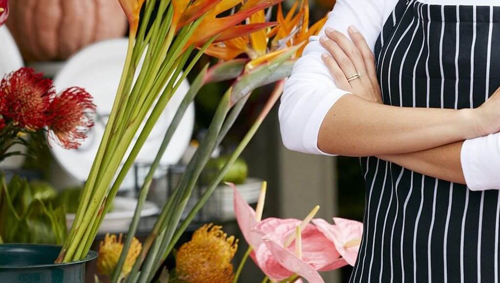 The Entrepreneurial Story Of Appleyards Tash Khan - image- woman with arms folded next to flowers